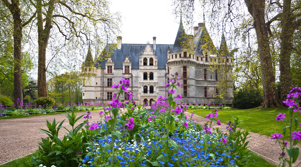 Colourful flowers in the foreground with a huge French turreted castle behind